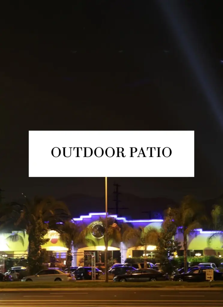 Text graphic reading Outdoor Patio over the venue's illuminated exterior at night