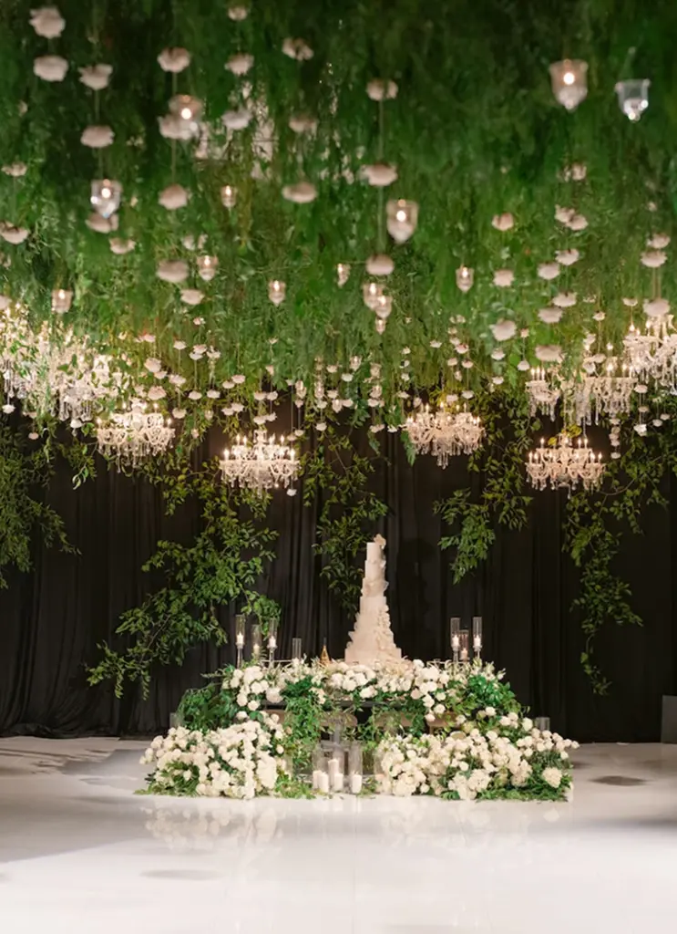Hanging greenery and floral installation over an elegant wedding cake display