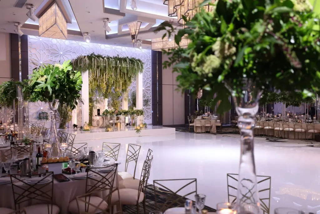 Ballroom set for a reception with a hanging greenery installation and white dance floor