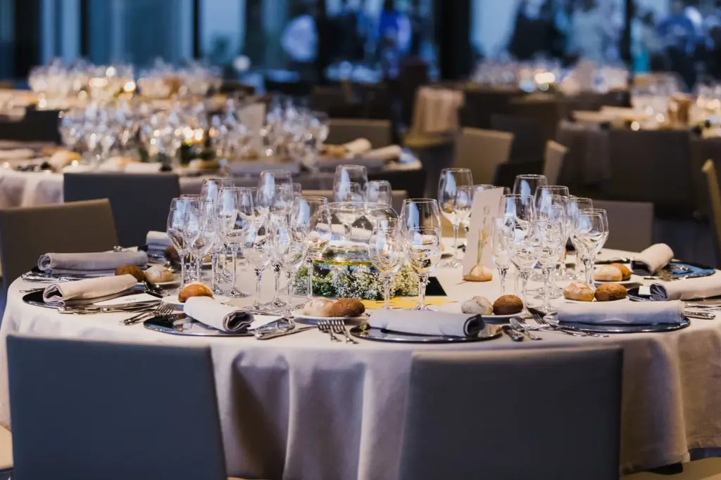 Round banquet table set with wine glasses, plates and a floral centerpiece