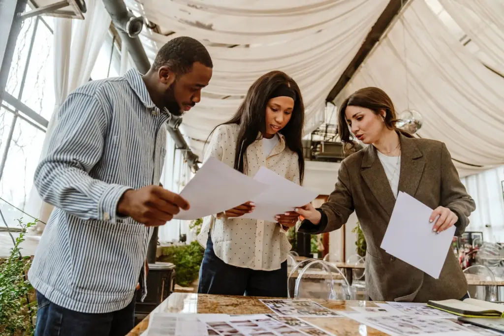 Event planning team reviewing printed layouts at a table in a draped venue