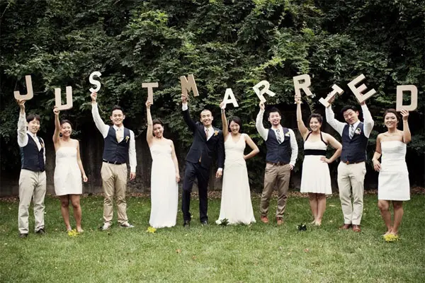 Wedding party holding oversized JUST MARRIED letters in a garden