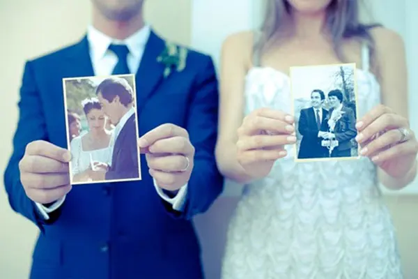 Bride and groom each holding a vintage wedding photo of their parents