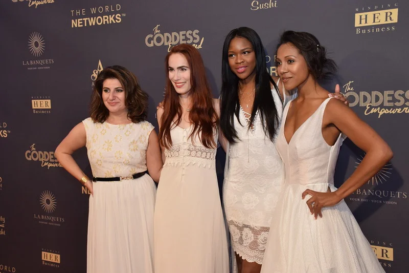 Four women posing at The Goddess Empowered step-and-repeat backdrop