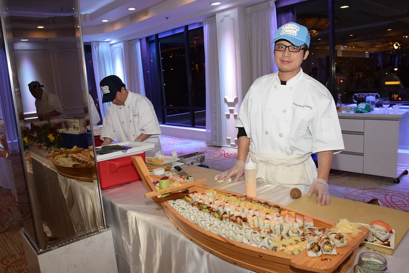 Chef preparing a sushi boat display at a catered event