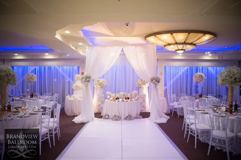 Reception setup with a white draped chuppah and blue uplighting at Brandview Ballroom