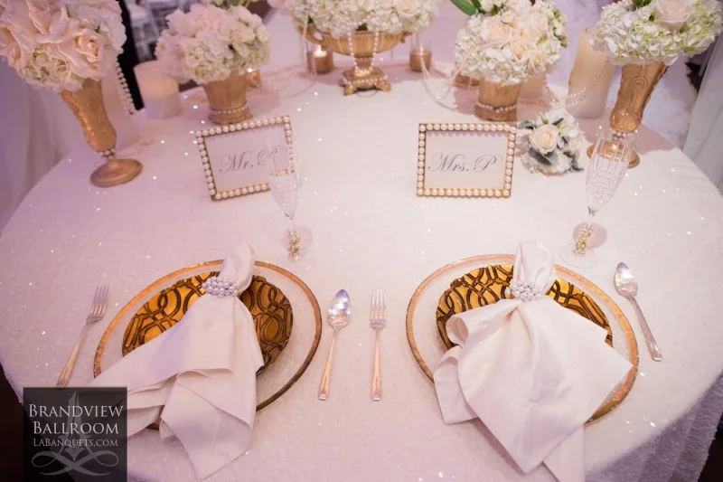 Place setting with gold chargers, white florals, and Mr. and Mrs. cards at Brandview Ballroom