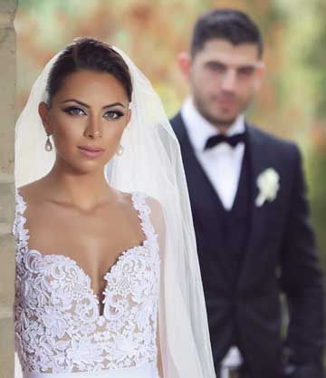 Close-up portrait of a bride outdoors with the groom blurred in the background