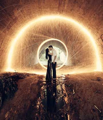 Couple kissing inside a tunnel lit by a glowing circular light trail