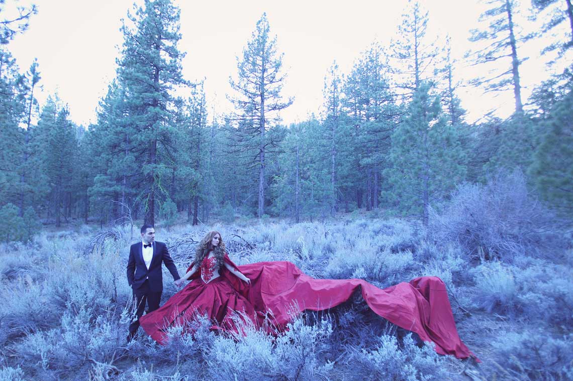 Couple in a forest clearing, the woman wearing a long flowing red gown