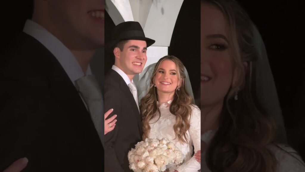 Close-up of a smiling bride and groom, the groom wearing a black fedora