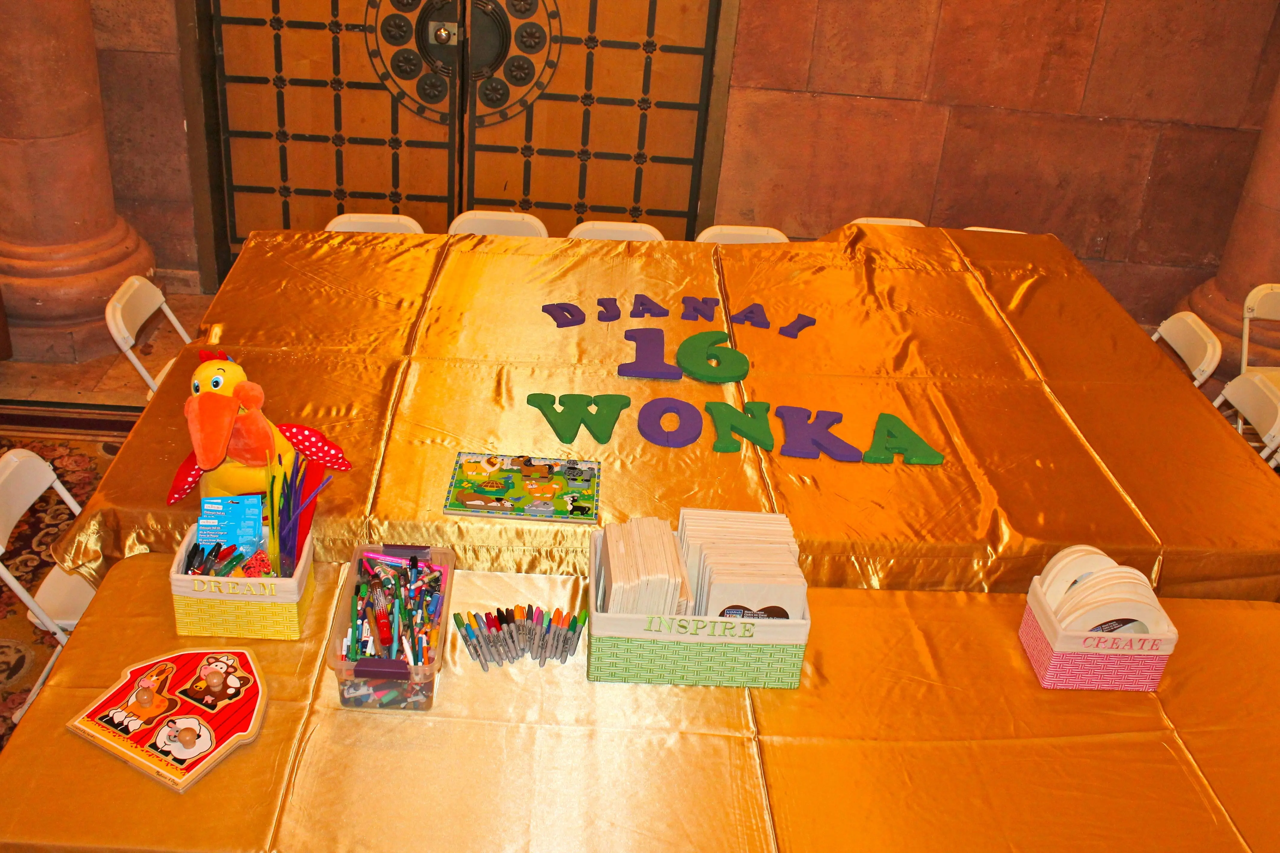 Gold-covered craft table with 'Djanai 16 Wonka' lettering at a birthday prom event