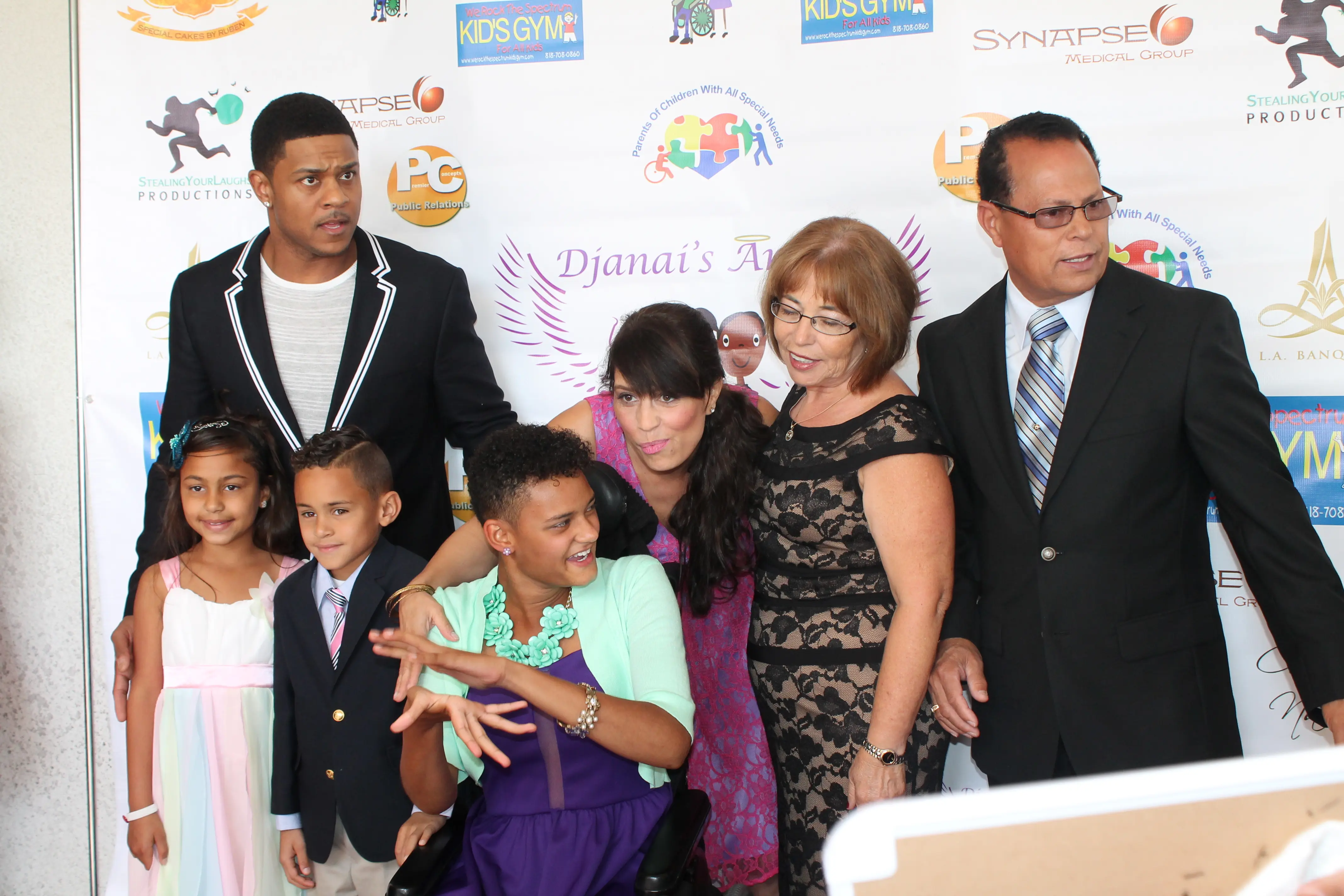 Family posing together on a red carpet at a charity prom step-and-repeat backdrop