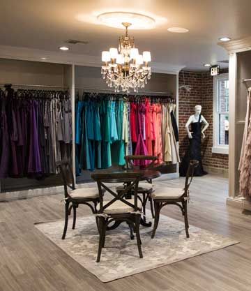 Bridal boutique interior with dress racks, seating area, and chandelier