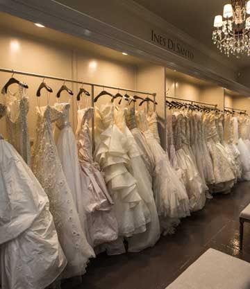 Rows of white wedding gowns displayed under an Ines Di Santo boutique sign