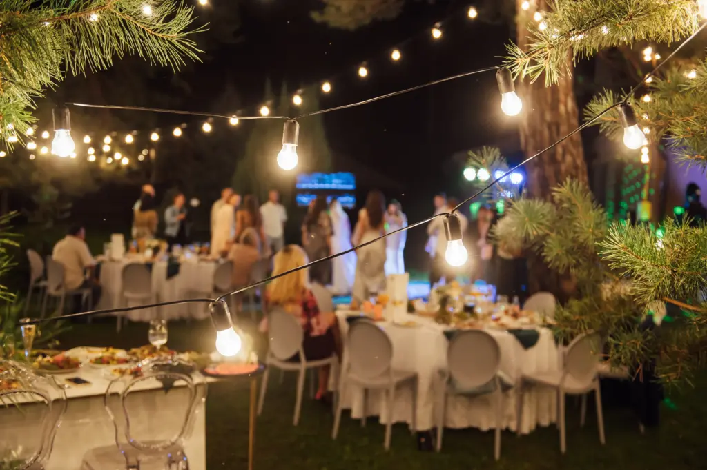 Outdoor evening reception with string lights and guests seated at dinner tables
