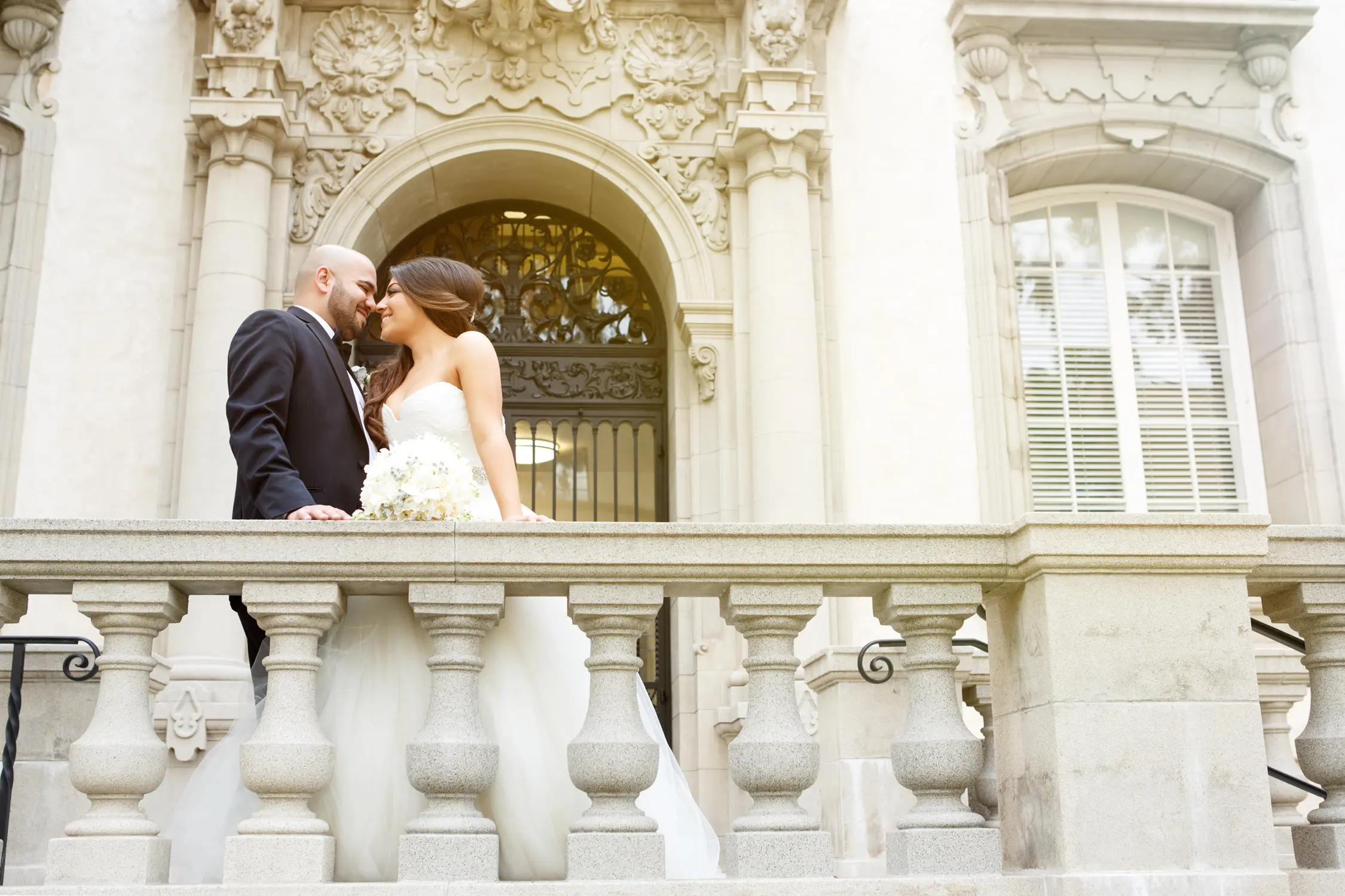 Bride and groom sharing an intimate moment on an ornate stone balcony