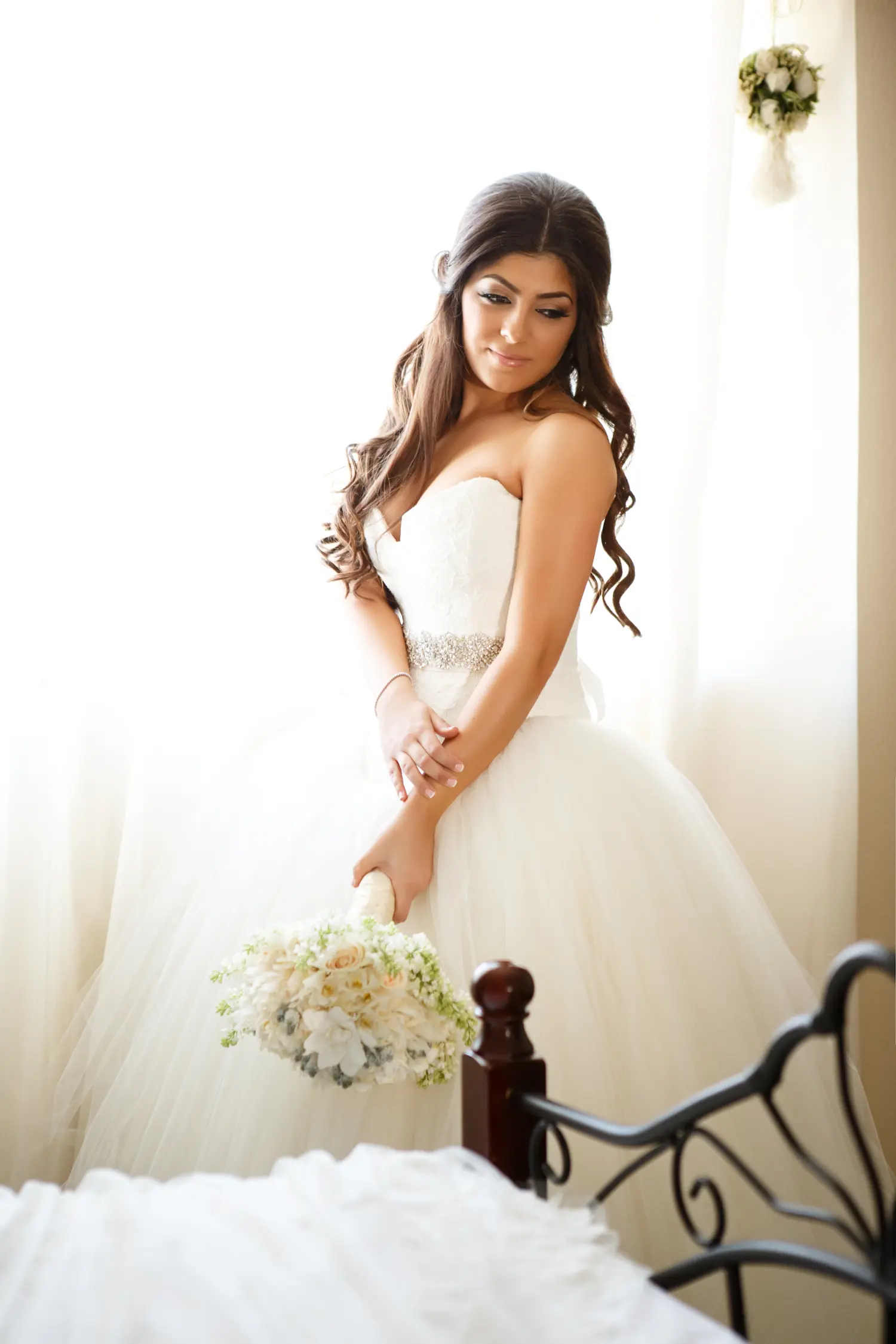 Bride holding her bouquet while getting ready in a bedroom