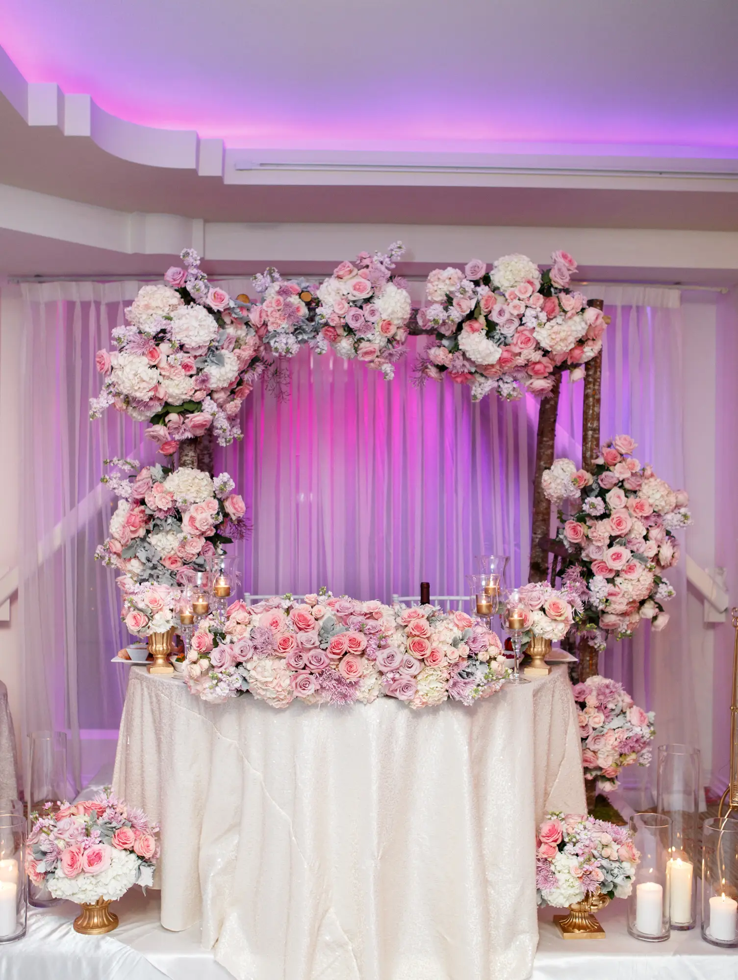 Floral-covered sweetheart table backdrop with pink and white blooms