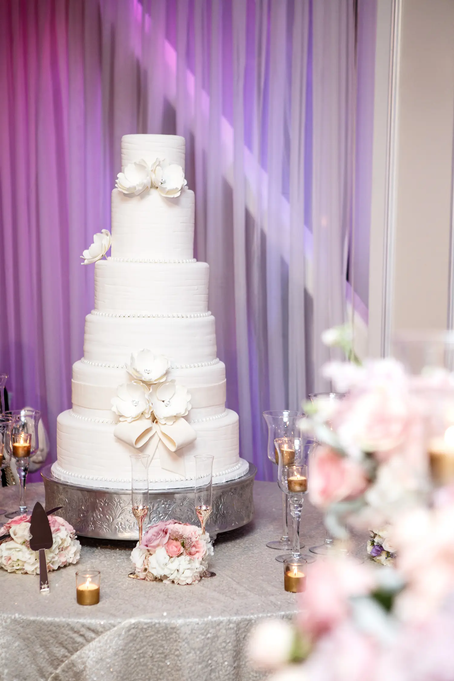 Five-tier white wedding cake decorated with sugar flowers