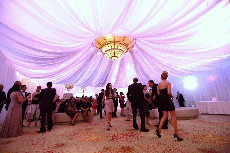 Guests mingling in a white-draped ballroom lounge area with a chandelier