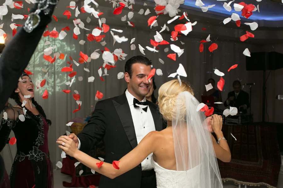 Bride and groom dancing as red and white confetti falls around them