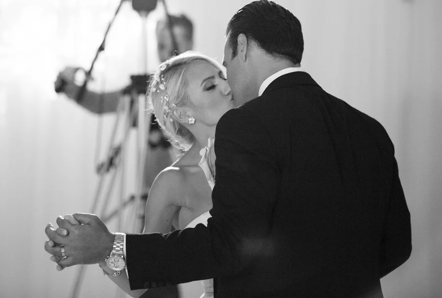 Bride and groom kissing while dancing together at their reception