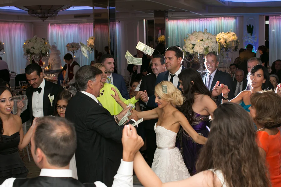 Wedding guests toss cash at the bride during a dollar dance at the reception