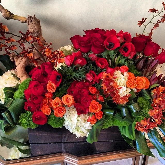 Red and orange floral centerpiece arrangement with driftwood accents
