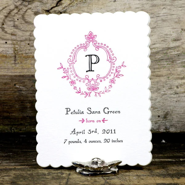 Cream cotton-stock announcement card with a pink monogram frame