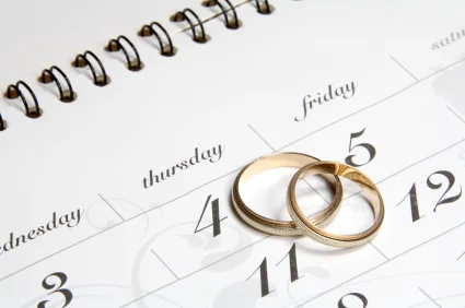 Two gold wedding bands resting on a calendar page