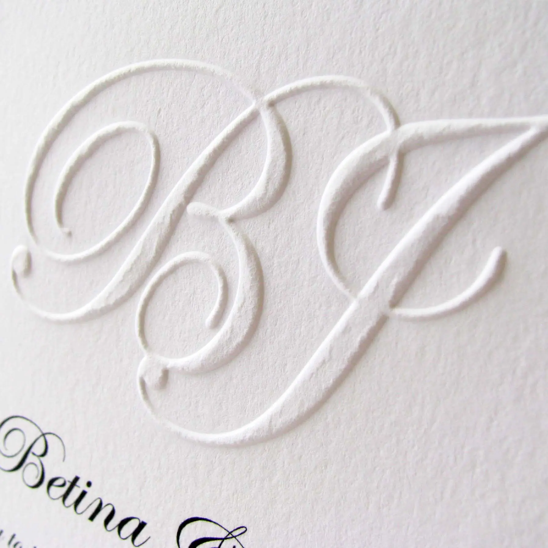 Close-up of a blind-embossed monogram on a wedding invitation