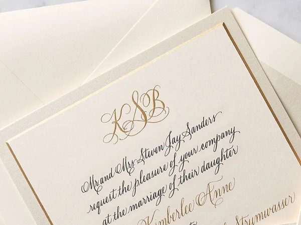 Gold engraved monogram and calligraphy on a wedding invitation