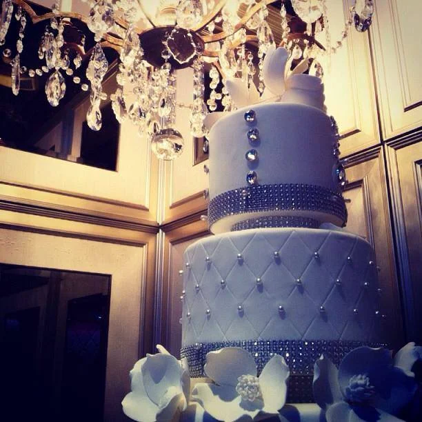 Tiered wedding cake with crystal banding beneath a crystal chandelier