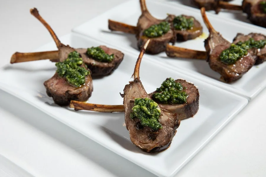 Grilled lamb chops topped with chimichurri on white plates