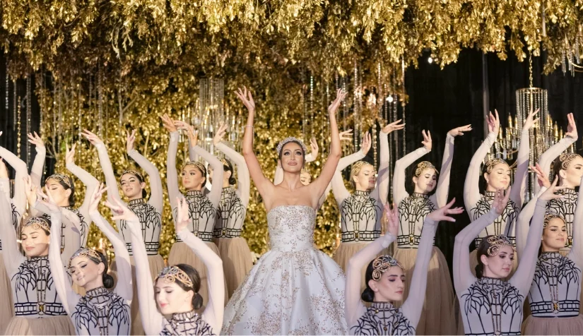 Ballet dancers in gold headpieces surrounding the bride under a gold leaf canopy