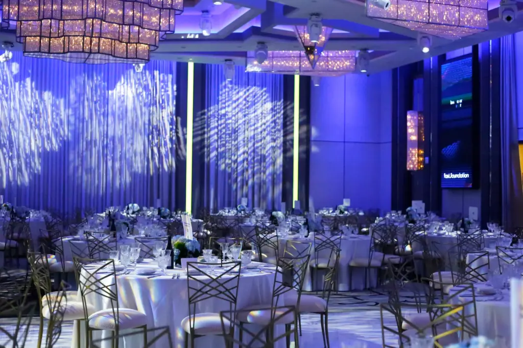Empty ballroom set with round tables under blue uplighting for a corporate gala