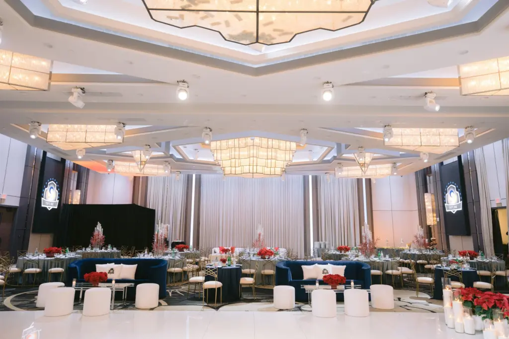 Banquet hall lounge with blue sofas, round dinner tables, and layered crystal chandeliers