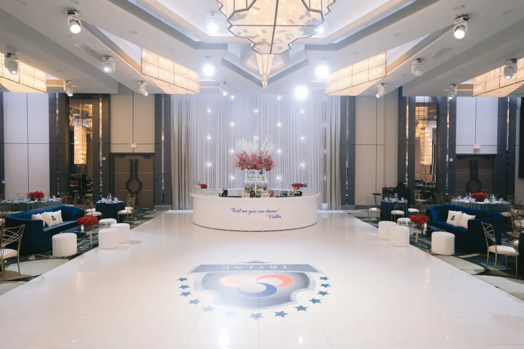 Reception lounge with dance floor, blue sofas, bar, and pendant chandeliers