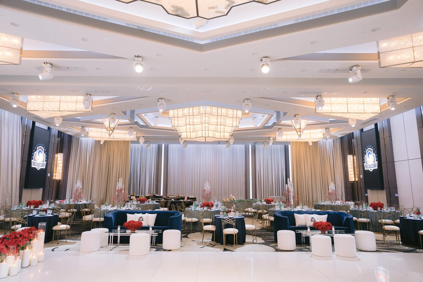 Elegant ballroom reception with gold chiavari chairs, white florals, and crystal chandeliers
