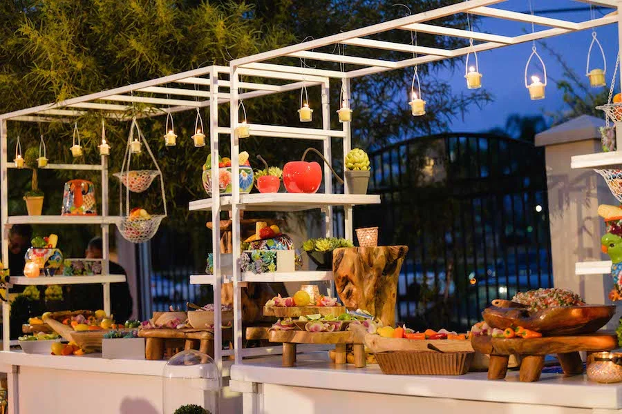 Evening dessert display station with hanging candles and fresh produce on wood shelving
