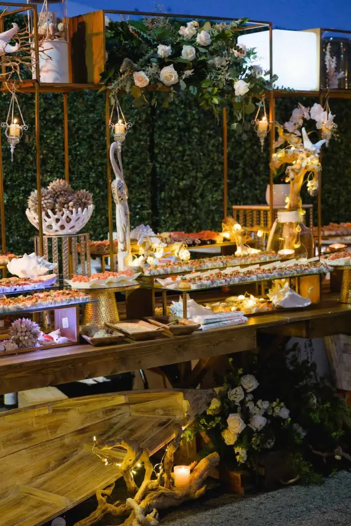 Illuminated buffet display with seafood, florals, and hanging lanterns at dusk