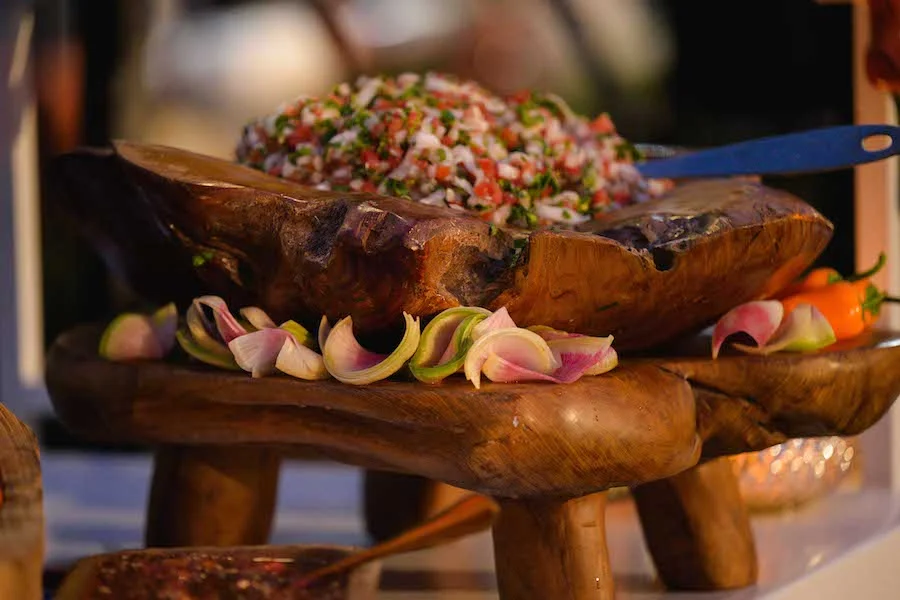 Chopped salad served on a rustic wood board with pickled onion garnish