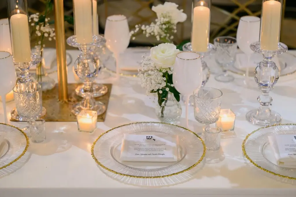 Close-up table setting with crystal candle holders, white florals and gold-rimmed plates