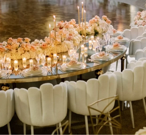 Curved banquet table with a white and blush floral garland and scalloped white chairs