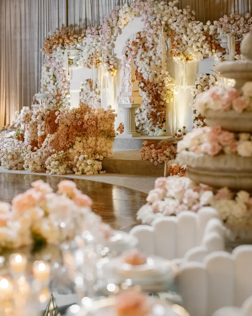 Stone tiered fountain decorated with pink and white rose garlands