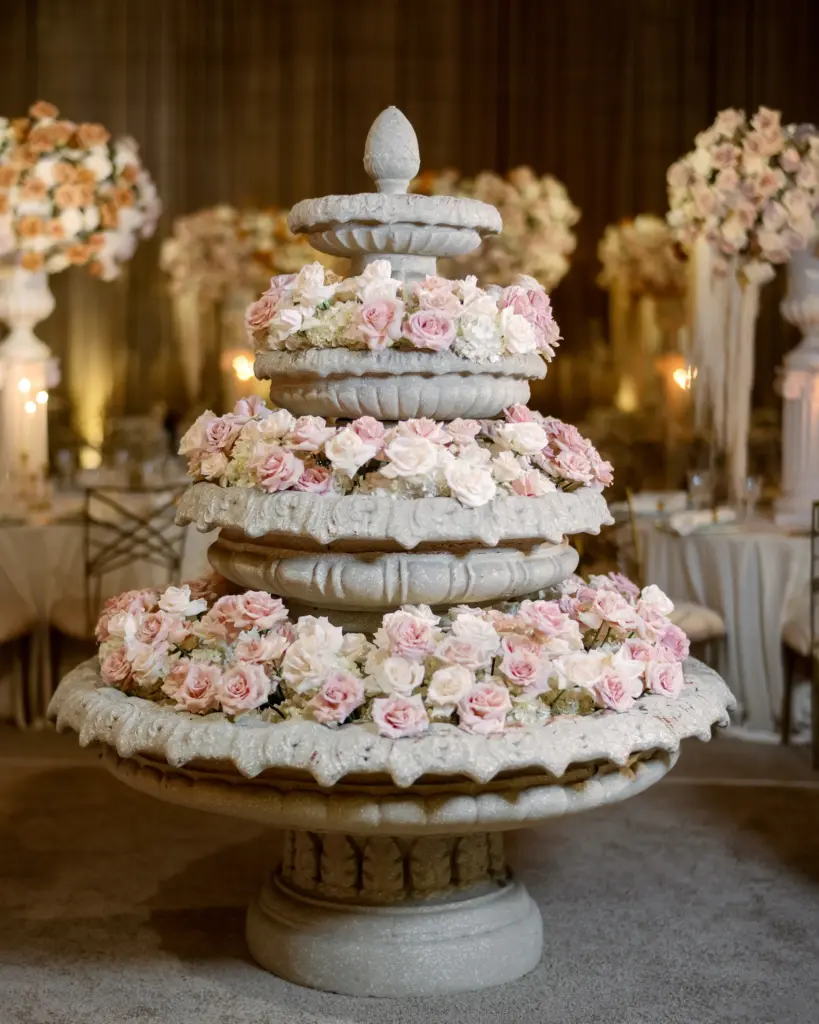 Three-tier stone fountain decorated with pink rose garlands
