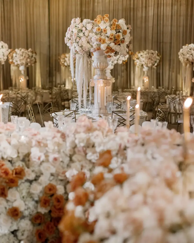 Reception hall with tall pedestal floral centerpieces and candlelit round tables