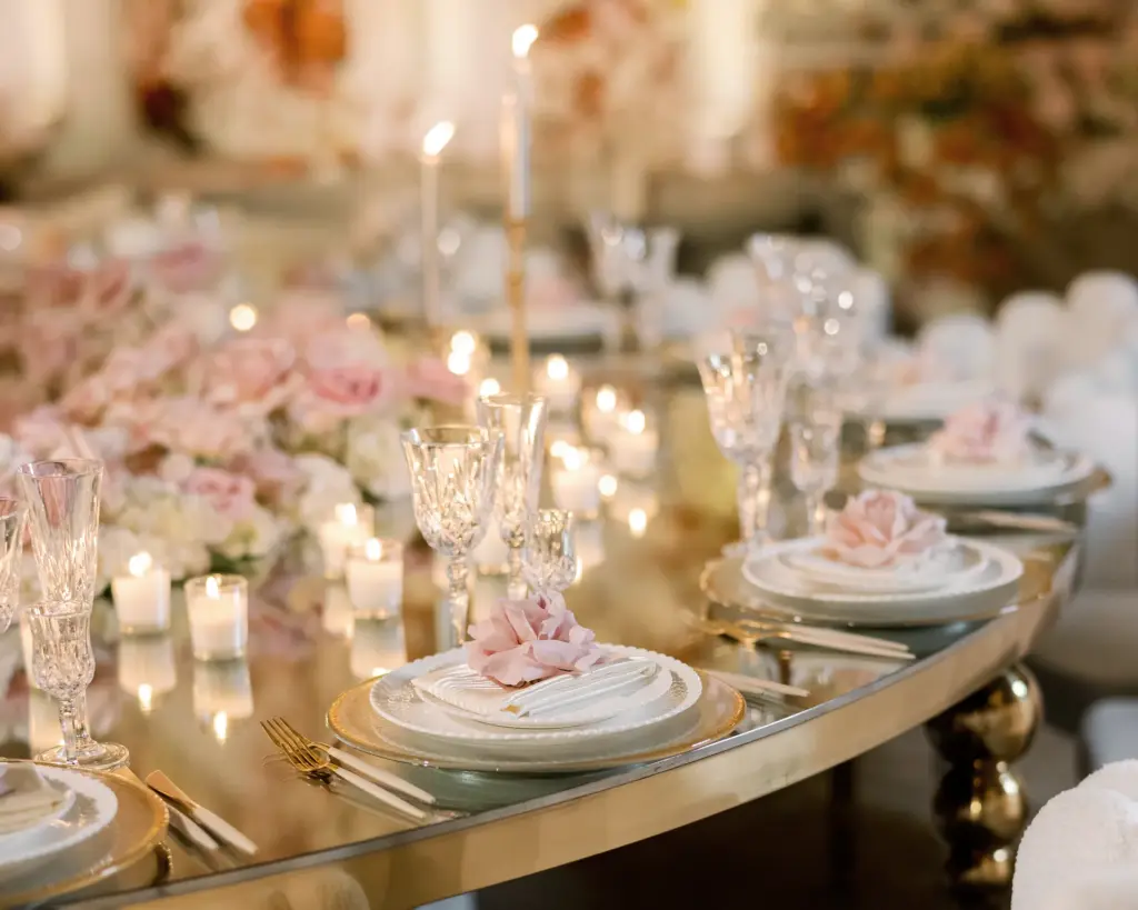 Elegant table setting with crystal glassware and blush rose and candle centerpieces