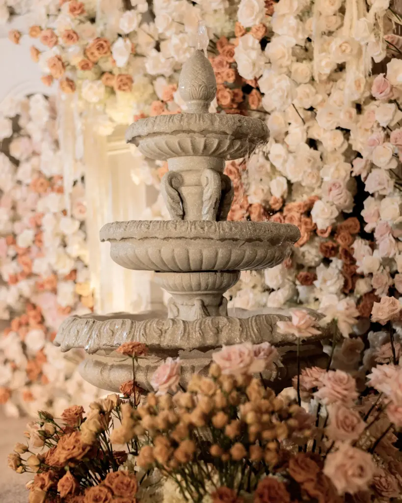 Close-up of an ornamental stone fountain tier amid pink and white roses